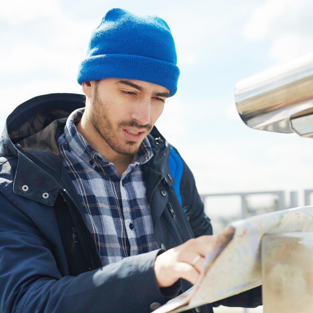 Person bundled in winter clothing looking at a map outdoors, representing winter preparation and winterization services.